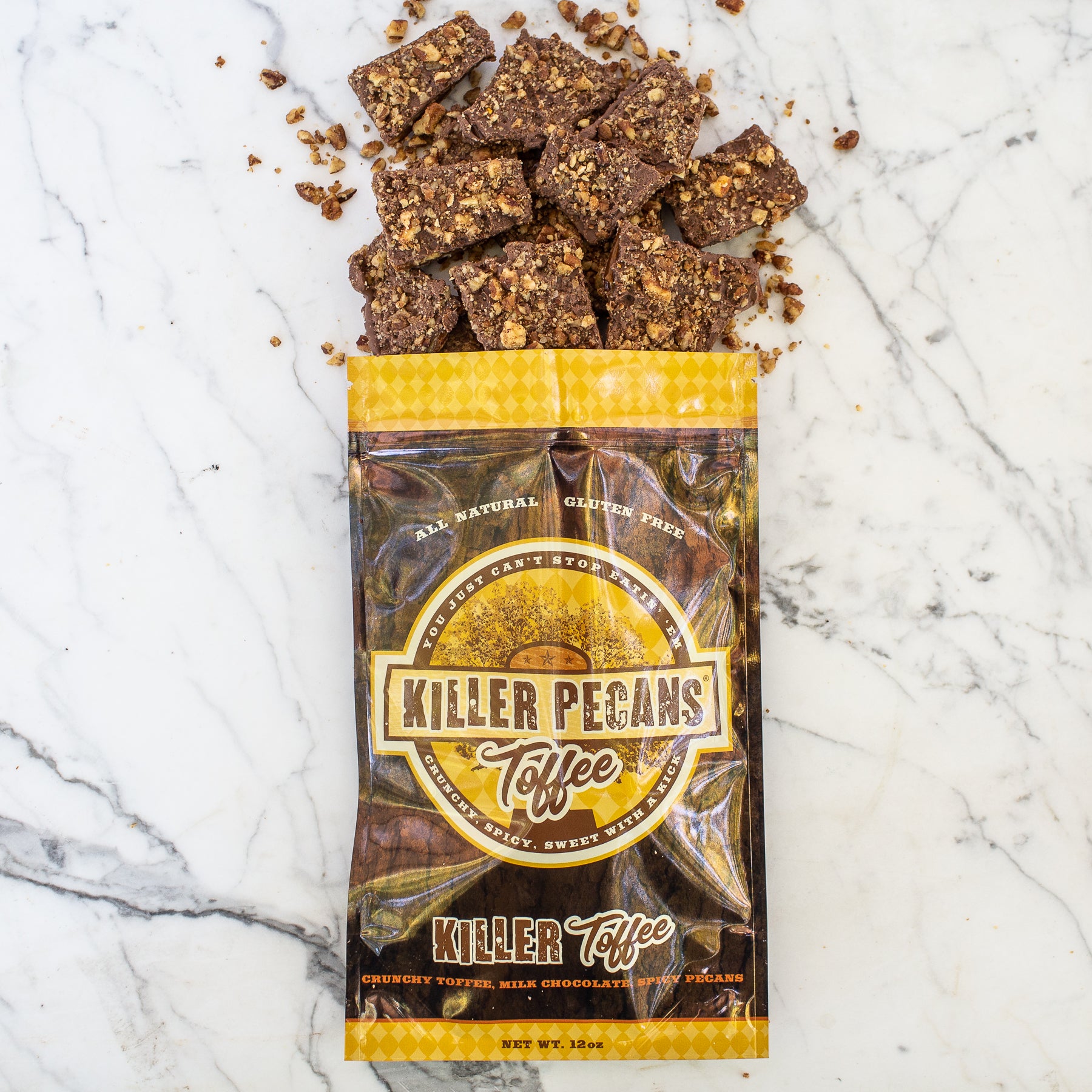 12 oz Killer Pecan Toffee Bag. Flat lay of the Killer Pecan Toffee Bag with Milk Chocolate, Killer Pecan Toffee Spilling out.